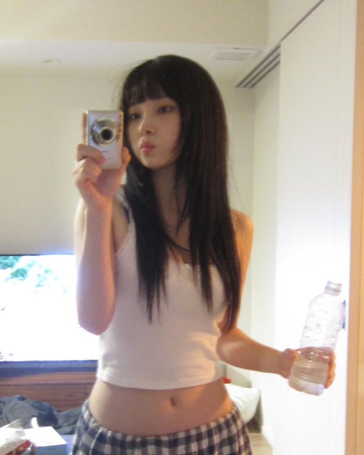 a young woman taking a selfie with her cell phone and water bottle in hand