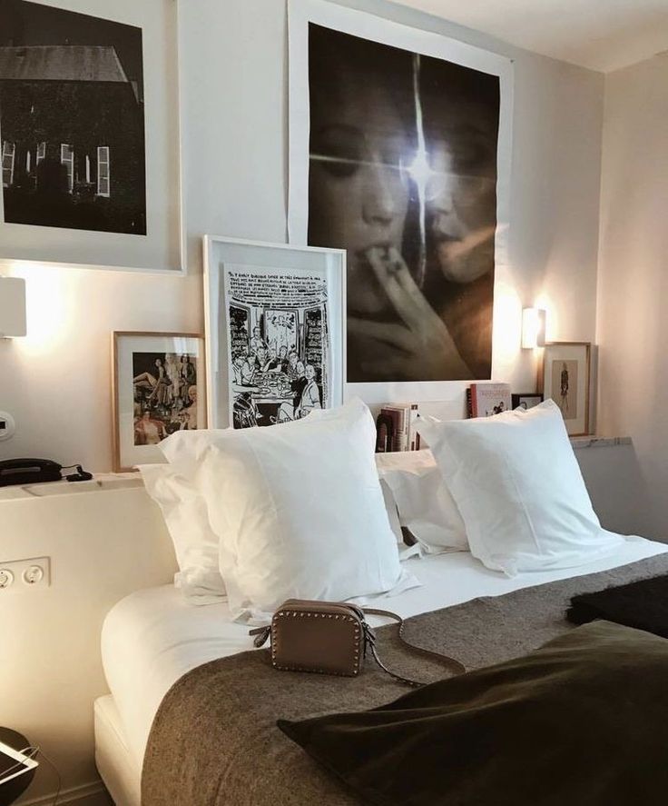 a bed with white pillows and pictures on the wall next to it in a bedroom