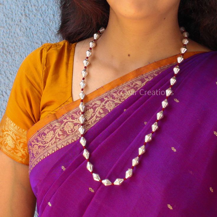 Silver Dholki (Bhoar) beads single line necklace is made of 92.5 silver beads woven with maroon thread, adjustable thread attached to adjust length. The silver bead is around 8mm. Dholki is a Marathi word that refers to a two headed hand drum, hence the necklace made using drum shaped beads or motifs is known as Dholki necklace. This jewellery is popular in the state of Maharashtra and is one of the traditional jewellery used in this region. For this beautiful handcrafted necklace if you prefer White Polished Beads For Temple Jewelry, Adjustable Silver Traditional Mala, Silver Beaded Temple Jewelry Necklace, Traditional Silver Pearl Necklace With Polished Beads, Traditional Silver Pearl Necklace With Round Beads, Traditional Silver Single Strand Necklace, Traditional Necklaces With Tiny Oval Beads, Traditional Silver Beaded Mala, Silver Hand-strung Necklaces For Festivals