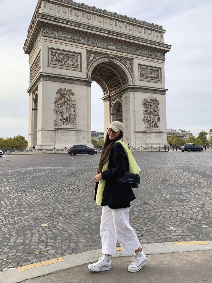 a woman standing in front of the arc de trio triumph