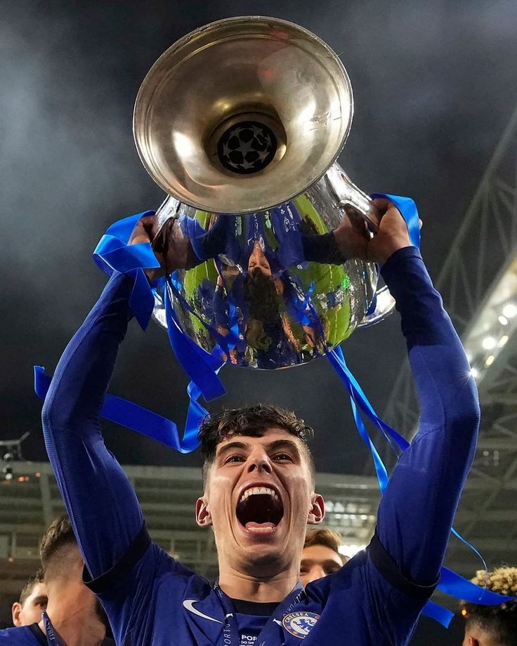 a soccer player holding up a trophy in the air with his hands and mouth wide open