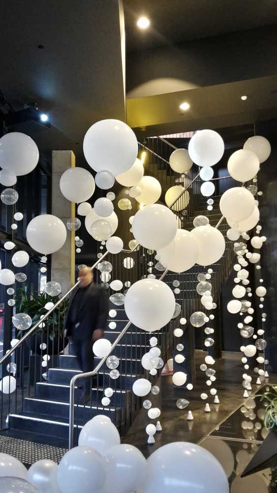 white balloons are floating from the ceiling in front of stairs and railings at an event