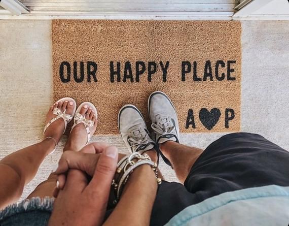 two people standing in front of a happy place door mat