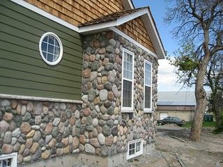 there is a house made out of rocks on the side of the building with a tree next to it