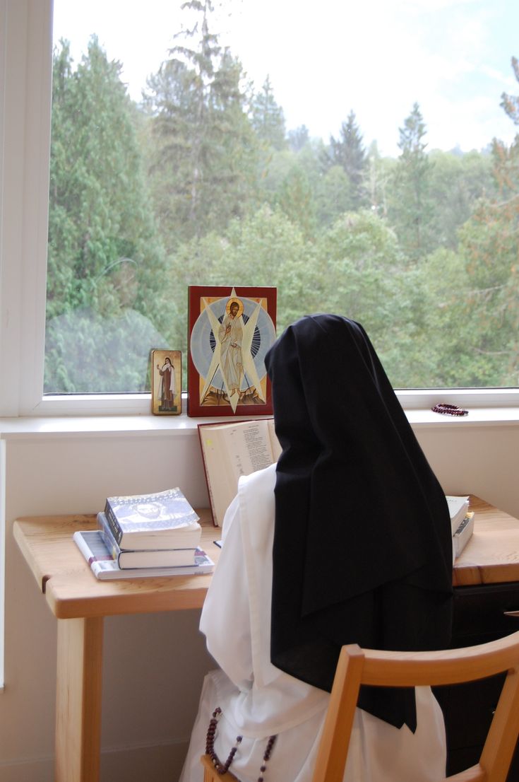 a woman sitting at a desk in front of a window with a book on it