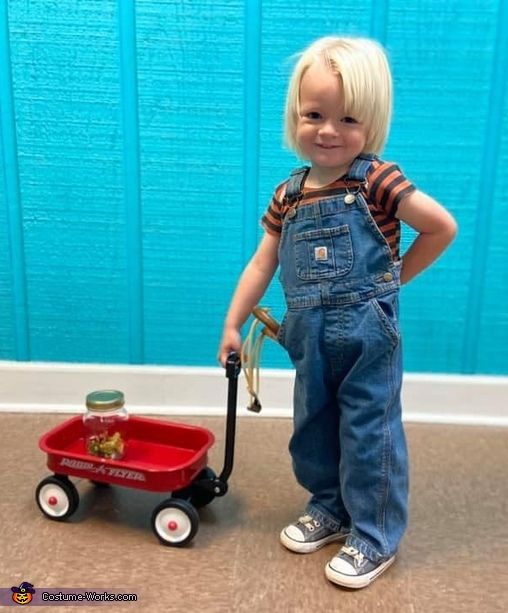 a little boy that is standing next to a red wagon