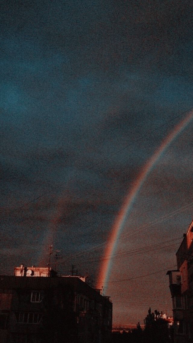 a rainbow appears in the sky over some buildings