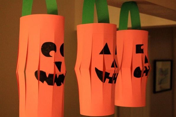 three orange paper bags with faces on them hanging from the ceiling in front of a mirror