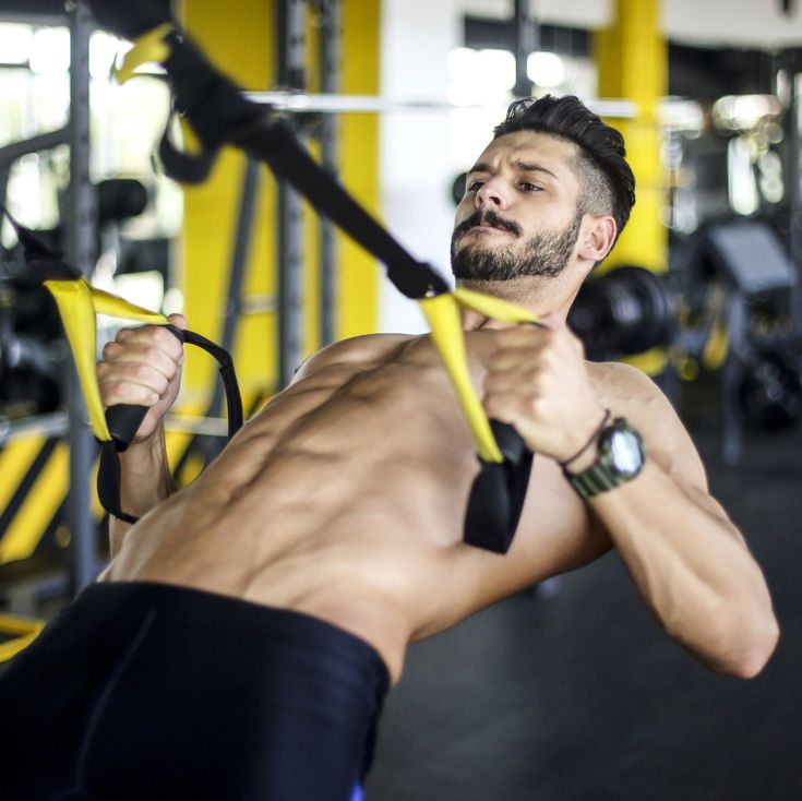 a shirtless man is doing exercises in the gym while holding a pair of yellow handles