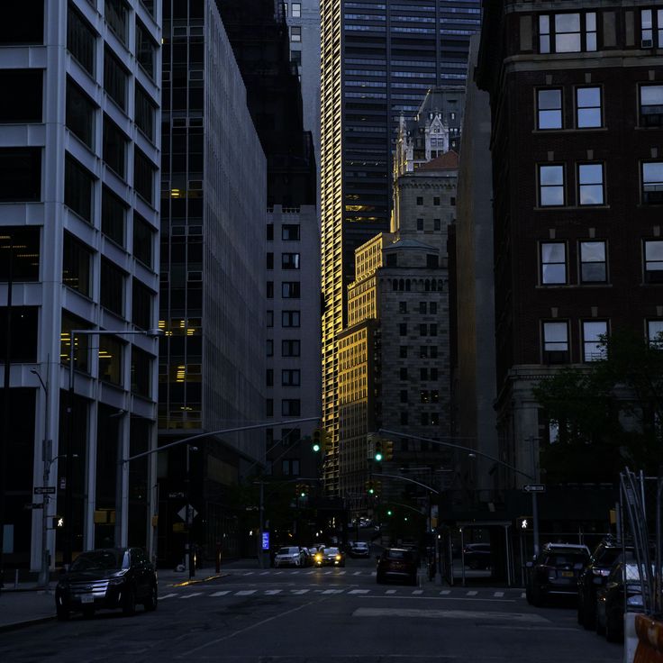 an empty city street at night with tall buildings in the background and traffic lights on both sides