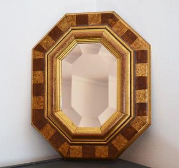 a mirror sitting on top of a wooden shelf next to a white wall and black table