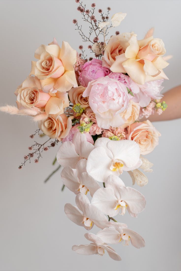 a person holding a bouquet of flowers in their hand with the background white and pink