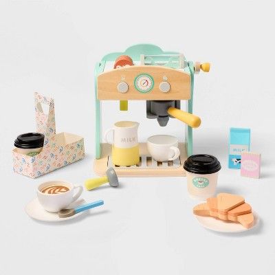 a toy coffee maker with cups and saucers next to it on a white surface