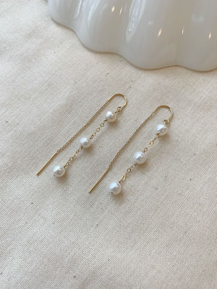 "These dainty Pearl threader earrings are classic and minimal. They look lovely paired with your special occasion outfits or a night out! The chain \"threads\" through the ear and stays in place!  Details: * Choose from 925 Sterling Silver or 14K Gold Filled * 5mm off round white Pearls * Approximately 2.25\" length * Made with all hypoallergenic materials 🤍 ✨ See all Pearl Jewelry here!: https://etsy.me/3zMbXyh WHAT TO KNOW ABOUT YOUR MAGBEE JEWELRY PURCHASE: 🤍 All MagBee pieces are safe for Dainty Chain Earrings, Delicate White Earrings With Adjustable Chain, Dainty White Pearl Drop Threader Earrings, White Dainty Pearl Drop Threader Earrings, White Dainty Threader Earrings With Pearl Drop, Minimalist Threader Earrings With Adjustable Chain For Wedding, Minimalist Wedding Threader Earrings With Adjustable Chain, White Adjustable Chain Dangle Threader Earrings, White Dangle Threader Earrings With Adjustable Chain