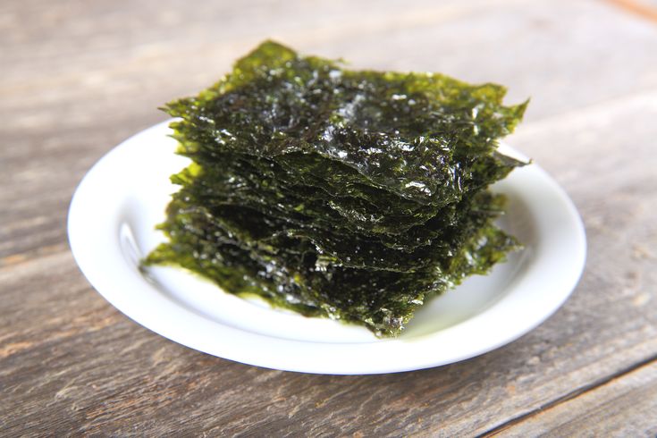 a white plate topped with seaweed on top of a wooden table