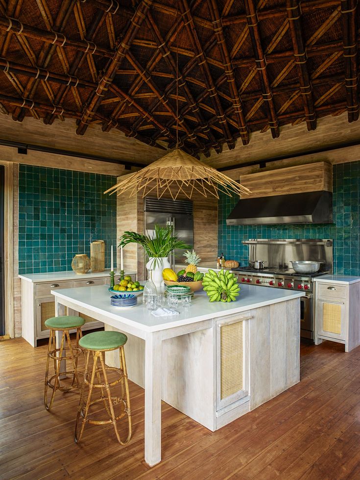 a kitchen with green tile walls and wood floors, an island countertop has fruit on it