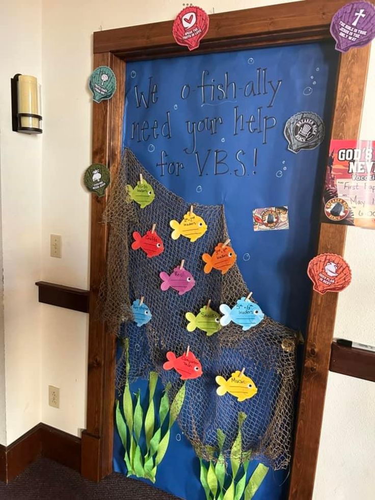 a door decorated with paper fish and seaweed for an ocean themed classroom door decoration