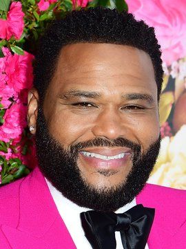 a close up of a person wearing a suit and bow tie with flowers in the background