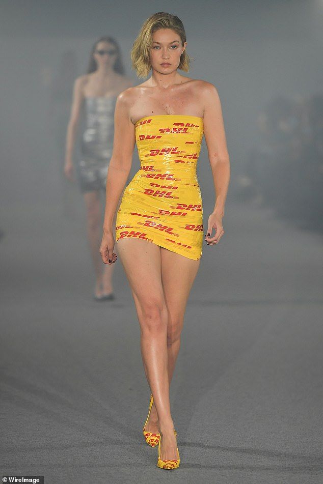 a model walks down the runway in a yellow dress