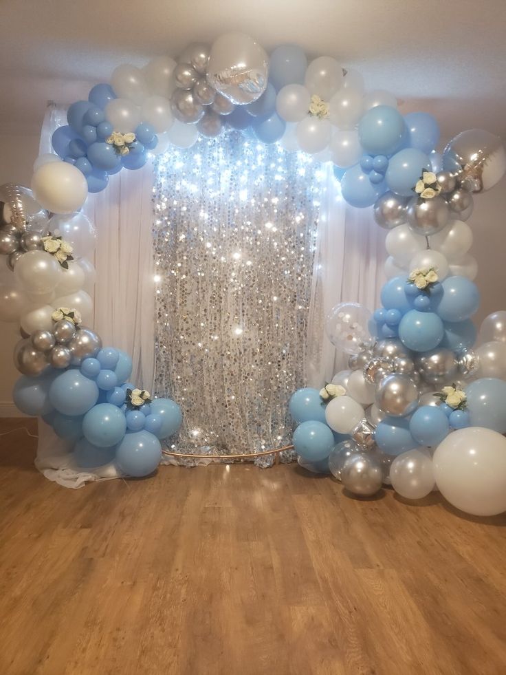 an arch made out of balloons and streamers in the middle of a wooden floor