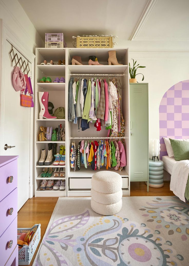 a bedroom with a bed, dresser and shelves filled with clothing on top of it