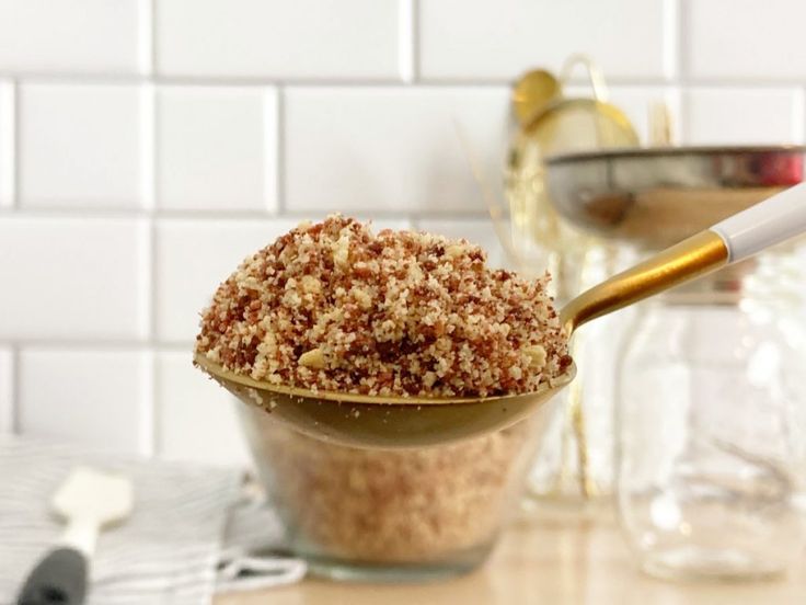 a spoon full of food sitting on top of a table next to a glass bowl