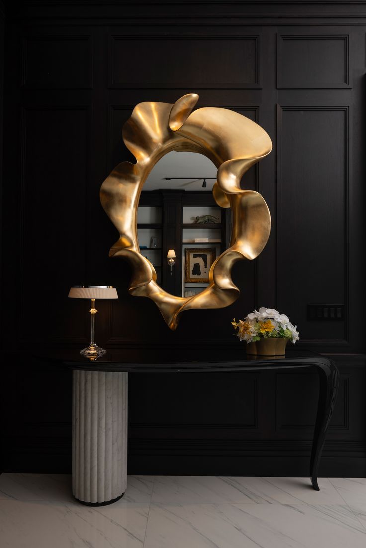 a black and gold console table with a round mirror on the wall next to it