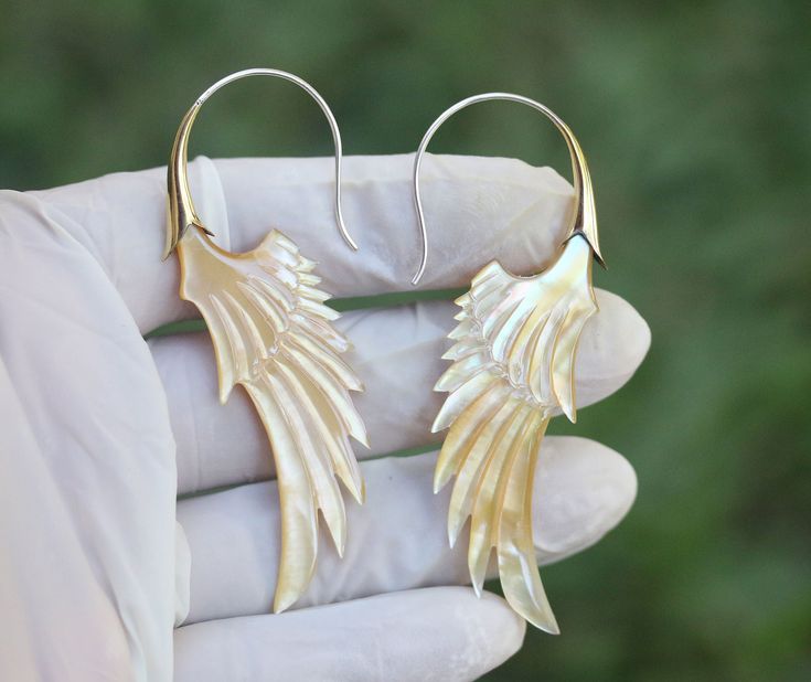 Wings earrings hand made MOP shells brass and silver post on the wearing parts , price per pair  Please have a look at Photos, colors may a little bit vary from the actual look, and due to Monitor Displayed settings and lighting when shoot with camera. SIZE please have a look at images for detail dimensions, size and weights. MAKE SURE YOU WANT THE WEIGHTS AND DIMENSIONS OF THE PRODUCTS SHOWED AT IMAGES URGENT AND IMPORTANT  THIS IS MANDATORY  NEW PROCEDURE FROM POST OF INDONESIA, ALL INTERNATIO Brass Shell Earrings For Gift, Unique Handmade Shell Earrings, Unique Gold Shell Earrings, Handmade Mother Of Pearl Shell-shaped Earrings, Unique Nickel-free Shell-shaped Earrings, Silver Shell Earrings For Pierced Ears, Unique Shell-shaped Earrings For Gift, Unique Silver Shell Earrings, Handmade Silver Shell Earrings