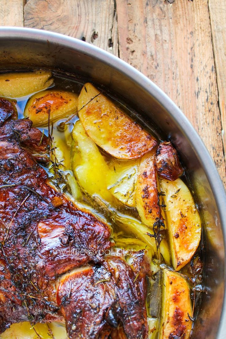 a pot filled with meat and potatoes on top of a wooden table