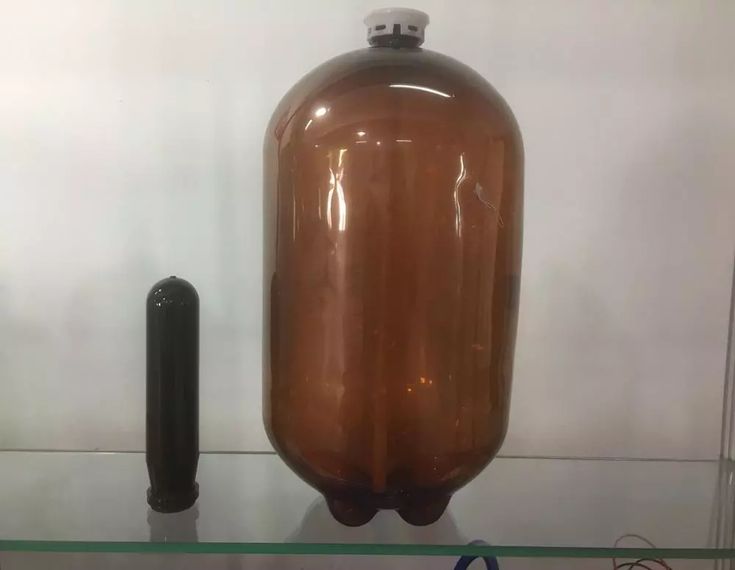 a large brown jug sitting on top of a glass shelf next to a black object