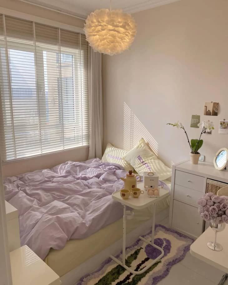 a bed room with a neatly made bed next to a dresser and window sill