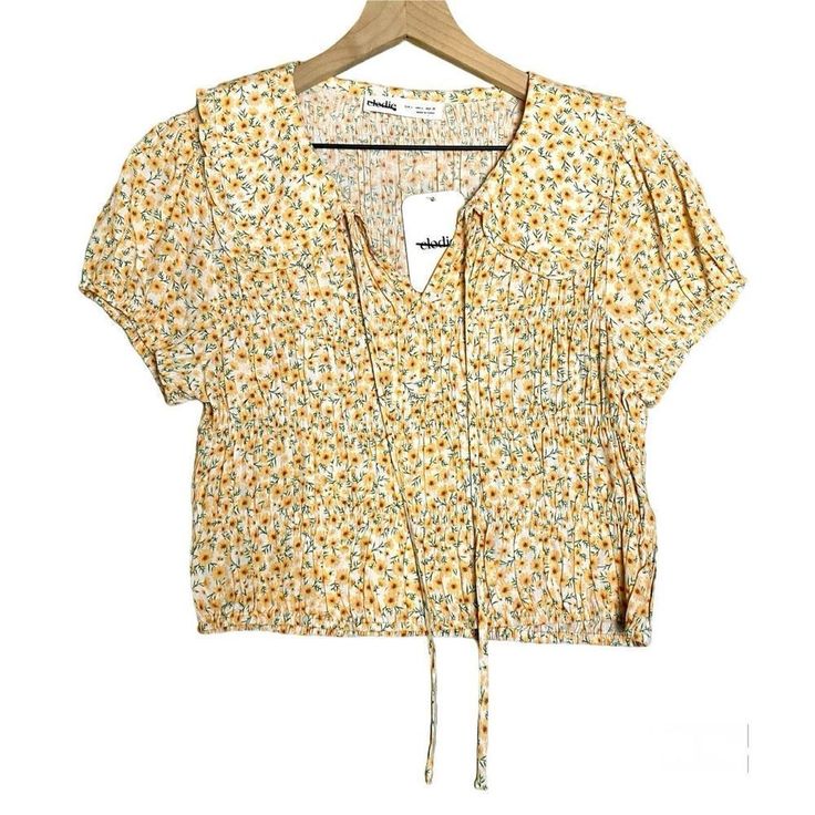 Elodie Smocked Peter Pan Collar Crop Top Ditsy Daisy Ecru/Yellow Size L New! New With Tag! Elodie Boho Smocked Peter Pan Collar Puff Sleeve Crop Top. All Over Smocking Makes This Top Very Flattering. Ditsy Print With A Cream Background And Yellow & Green Sunflowers. - Ruffle Detail - Peter Pan Collar - Puff Sleeves - Front Tie - Material: 47% Rayon 53% Viscose Size Large Please Carefully Review Photos For Condition Details & Measurements To Ensure A Perfect Fit! I Will Gladly Answer Any Questions You Have On The Item! Please Note, Measurements Are Approximate. Boho, Summer, Spring, Easter, Festival, Floral, Cottage Core, Beach Spring Yellow Cotton Smocked Top, Casual Beige Smocked Top For Summer, Yellow Cotton Smocked Top, Yellow Smocked Top For Summer, Yellow Smock Tops For Spring, Yellow Floral Print Top For Daywear, Casual Cream Top With Smocked Back, Beige Smock Tops For Summer, Casual Cream Tops With Smocked Back