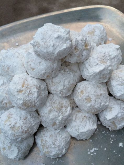 a pile of snowball cookies sitting on top of a metal tray