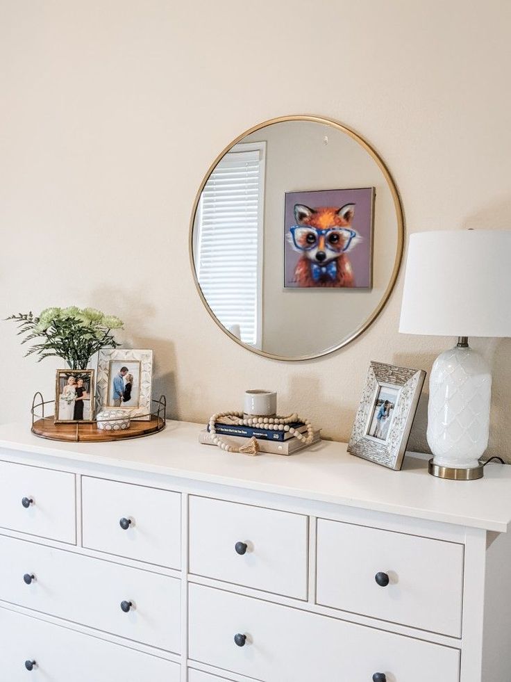 a white dresser topped with lots of drawers and a mirror on the wall above it