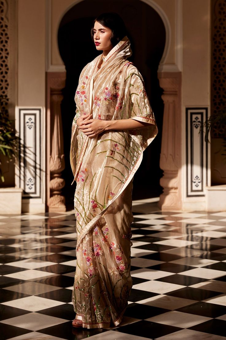 Silver saree in tissue fabric base embroidered with floral, bees in shell sequin motifs. Comes with unstitched blouse.
Components:2
Pattern:Embroidery
Type of Work:Floral, bees, shell sequin
Fabric:Saree - Tissue,  Blouse - Plain Satin
Color:Silver
Other Details:
Swarovski and cut beads motifs
Note: Blouse worn by the model is not for sale
Occasion:Destination Wedding - Aza Fashions Silver Saree, Floral Saree, Dresses Traditional, Saree Designs Party Wear, Cape Style, Indian Dresses Traditional, Embroidered Saree, Plain Blouse, Embroidery Floral