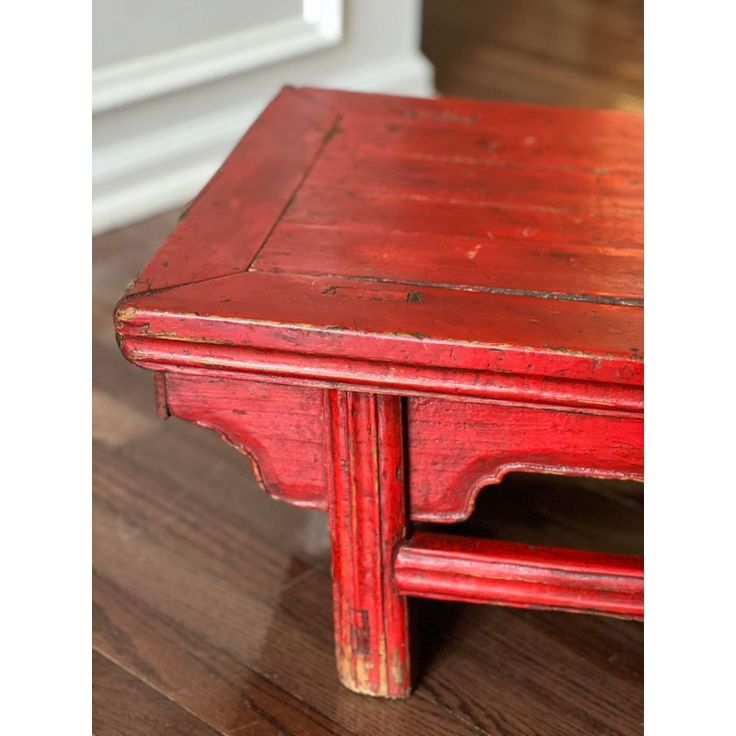 an old red wooden table sitting on top of a hard wood floor