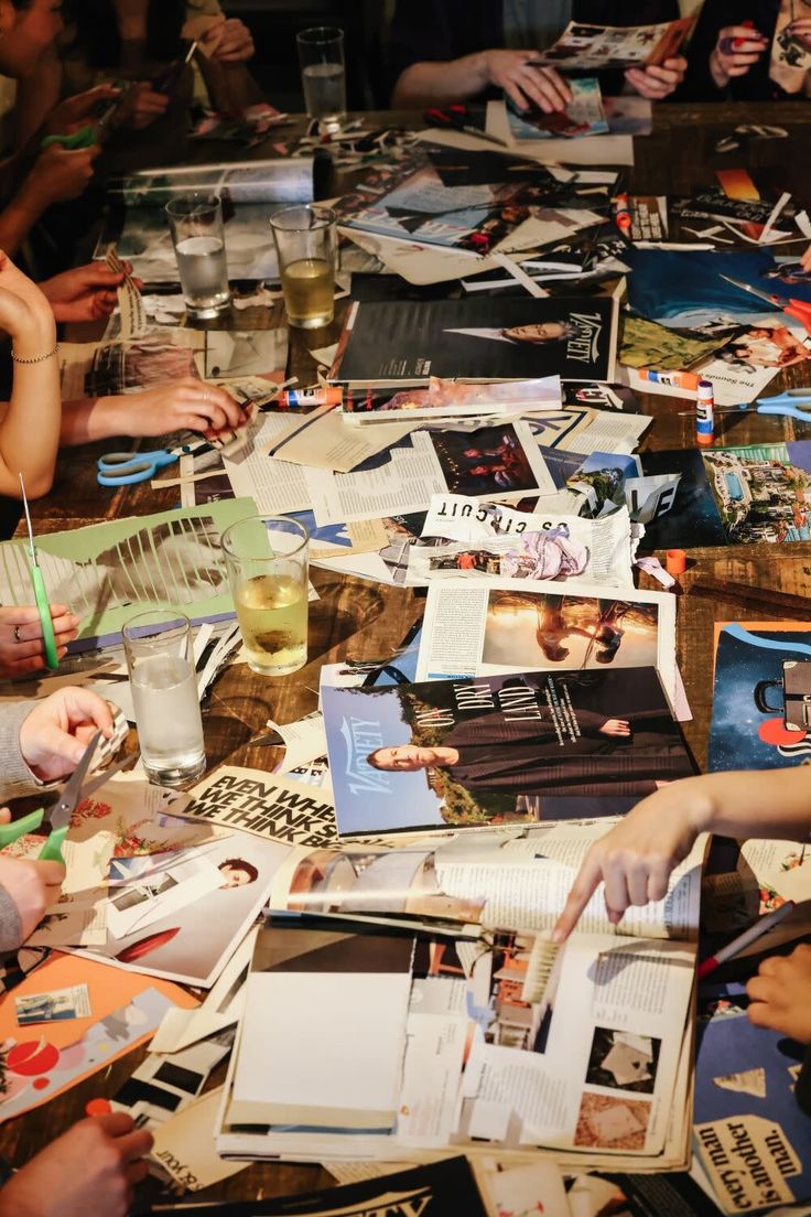 a large group of people sitting around a table with papers and pictures on it,