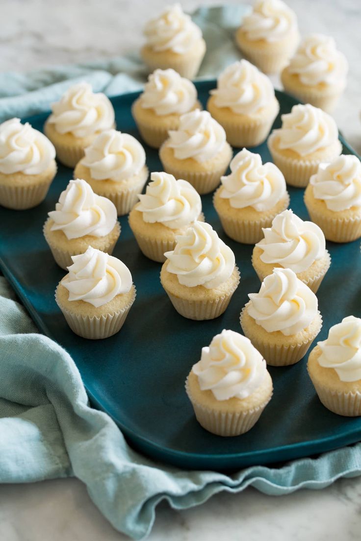 cupcakes with white frosting sitting on a green plate next to a blue towel