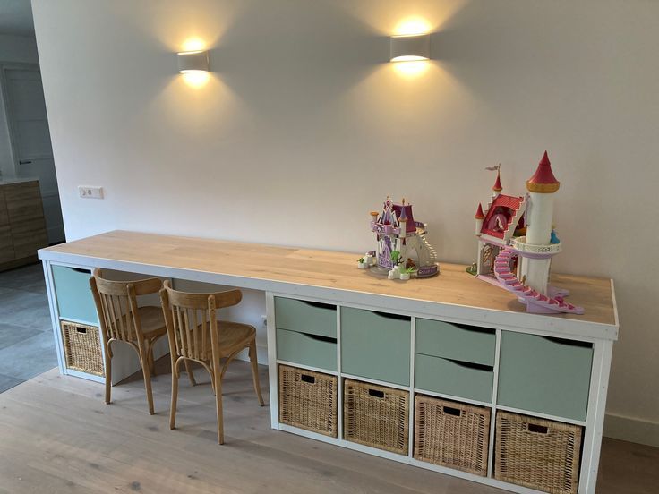 two chairs and a table with baskets on it in a room that has white walls