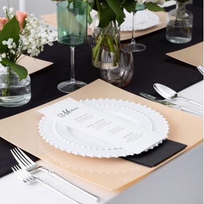 the table is set with white and black place settings, silverware and flowers in glass vases