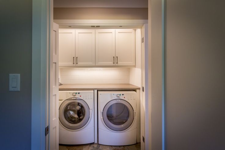 a washer and dryer in a small room with white cabinets on either side