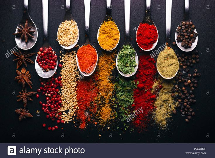 spoons filled with various spices on a black background