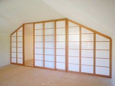 an empty room with white walls and wood trimmings on the wall, in front of a slanted ceiling