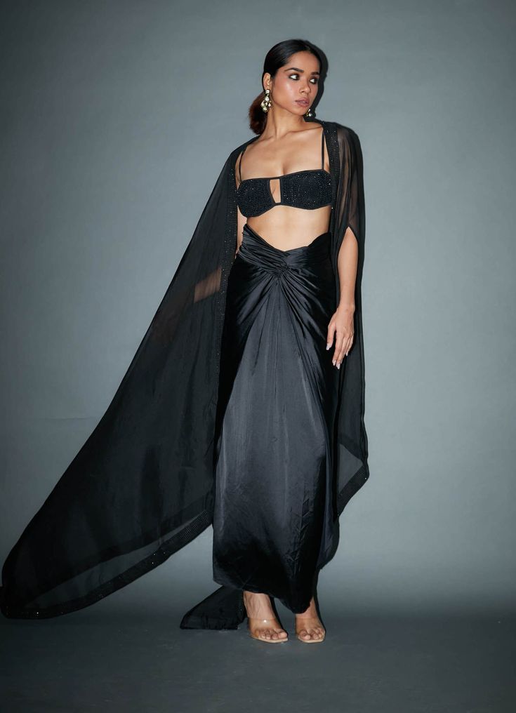 Make a bold and stylish statement with this black crystal embellished bralette, perfectly paired with a satin drape skirt and a matching cape. This ensemble radiates elegance and allure, ensuring you stand out at any special occasion or event. Silk Sets With Cape Sleeves For Evening, Silk Evening Sets With Cape Sleeves, Silk Evening Set With Cape Sleeves, Elegant Festive Sets For Cocktail Occasions, Elegant Festive Sets For Cocktail, Elegant Festive Cocktail Sets, Silk Set With Cape Sleeves For Party, Silk Sets With Cape Sleeves For Party, Silk Party Set With Cape Sleeves