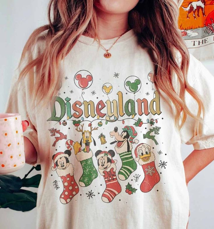 a woman wearing a disneyland christmas t - shirt with mickey mouse and friends on it