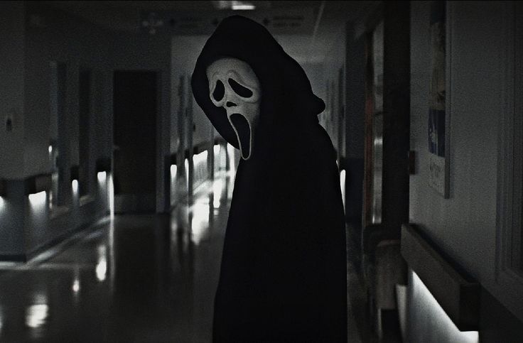 a person in a black robe with a ghost mask on