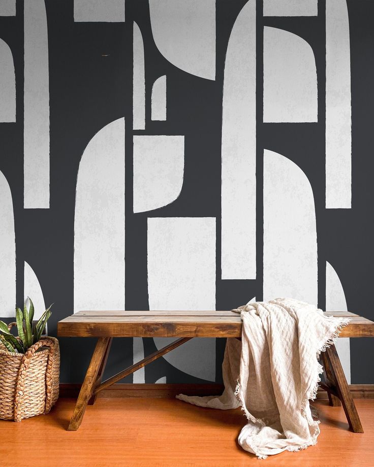 a wooden bench sitting in front of a black and white wall