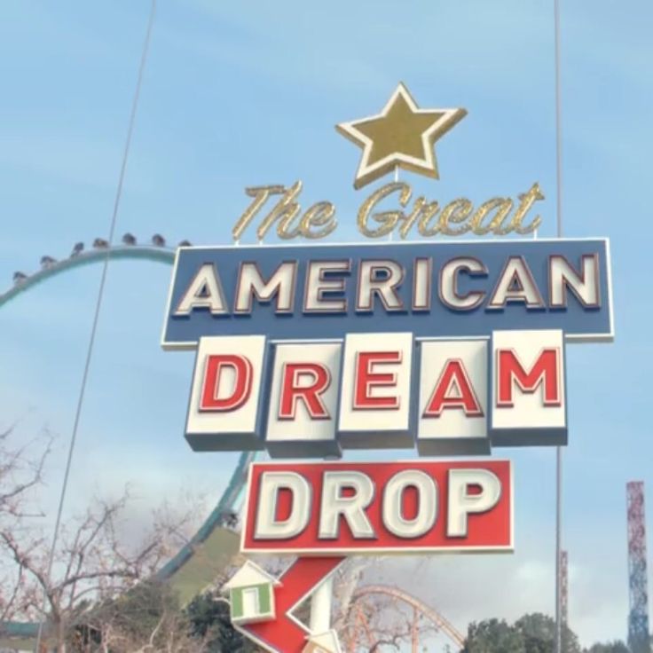 an american dream drop sign in front of a roller coaster at the theme park with a star on top