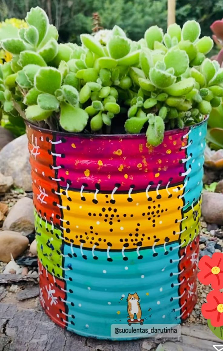 a colorful tin can planter with succulents in it