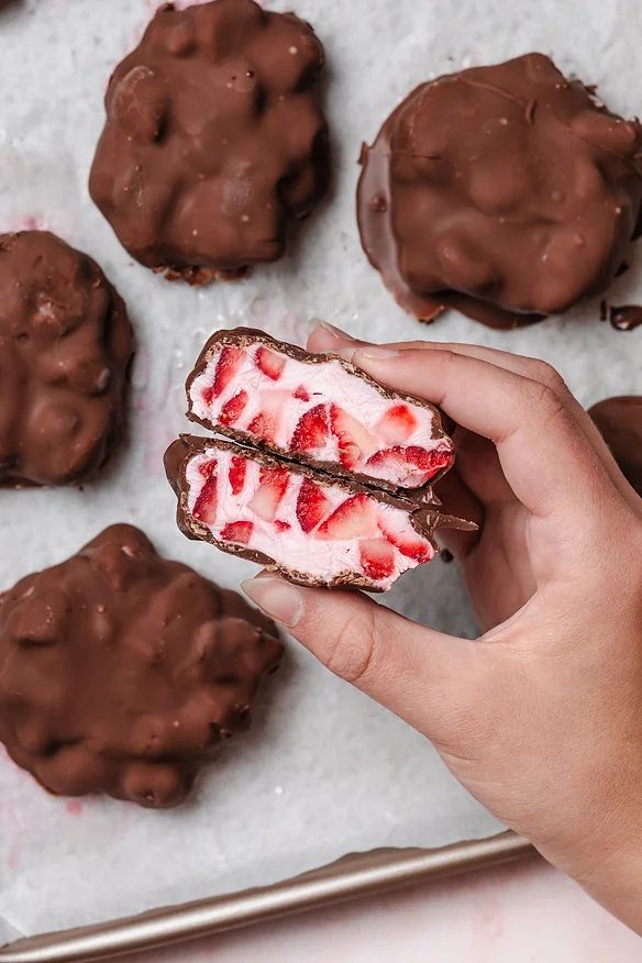 someone is holding some chocolate covered cookies with strawberries on them and they are ready to be eaten